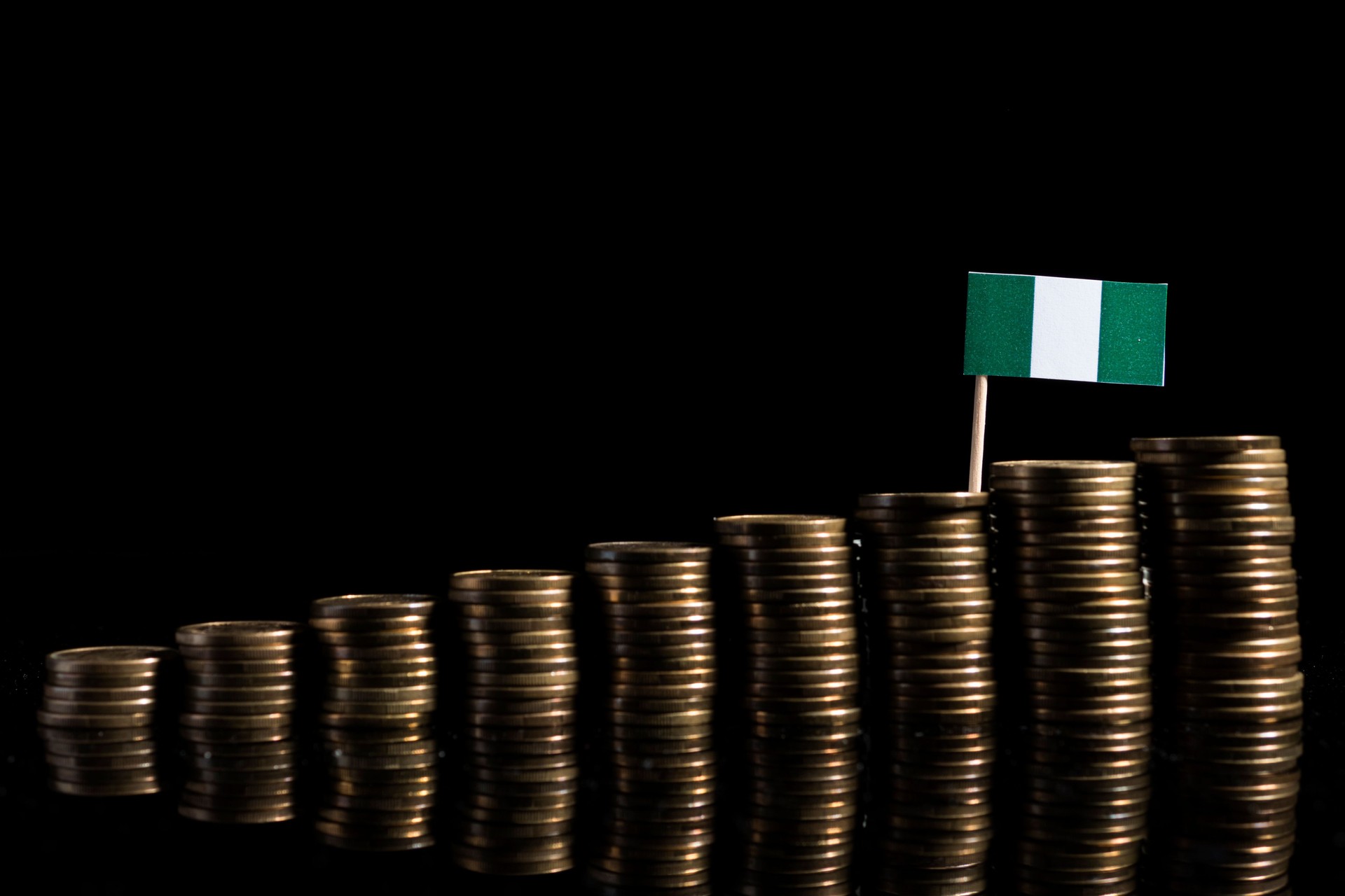 Nigerian flag with lot of coins isolated on black background